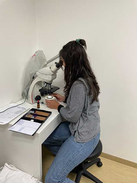 Studentischer Kliniktag: Studentin blickt durch ein Mikroskop.